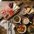 Apéritif dînatoire froid : planches de charcuterie, terrines, olives et crackers sur table en bois